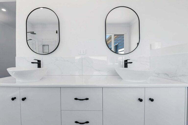 A white modern his and hers vanity unit with twin mixers, mirrors, black fixtures and quality cabinetry. Perfect for a master bathroom.