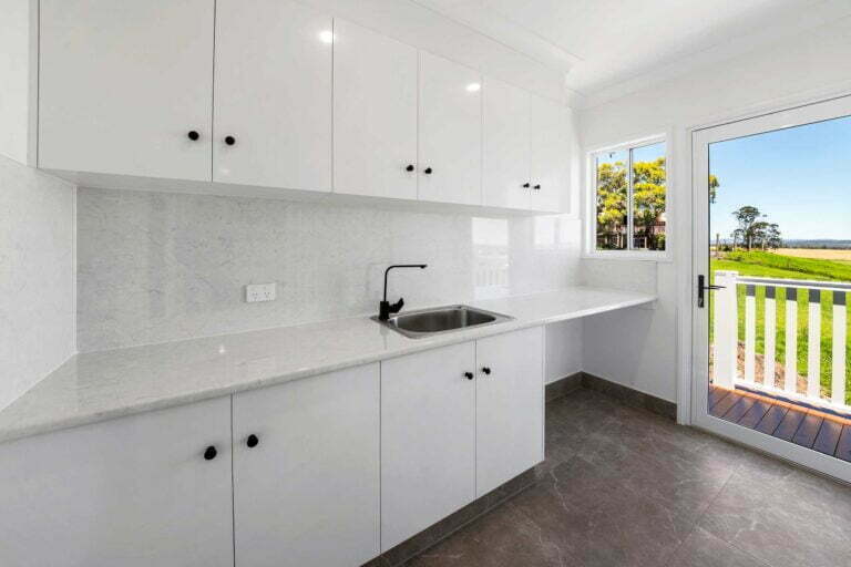 This laundry room is generous in space and provides a large amount of storage with overhand and under bench cupboards. The marble laminate benchtop is deeper than usual while also accommodating a wider entry / exit to the outdoor deck.